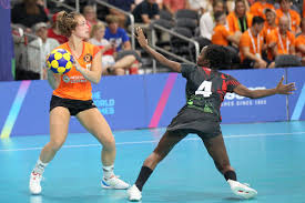 Actie tijdens een korfbalwedstrijd met een speelster in oranje tenue die de bal vasthoudt en wordt verdedigd door een speelster in zwart tenue, beide dragen enkelbraces