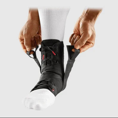 je ziet een been en twee handen die een mcdavid enkelbrace aantrekt