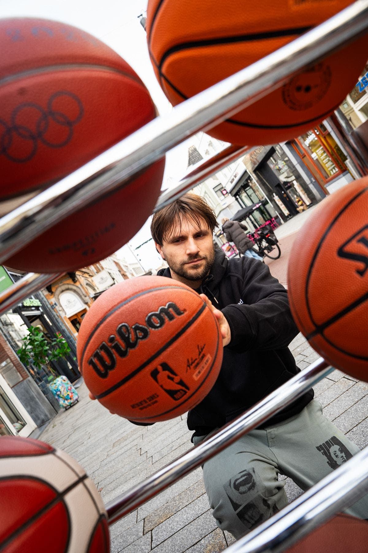 Achter het ballenrek van Burned houdt iemand een Wilson-basketbal naar voren