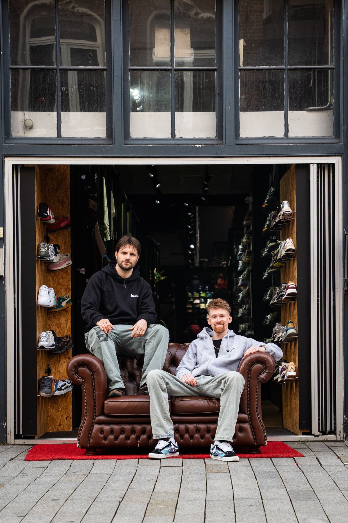 De open entree van Burned Sports aan de Hinthamerstraat 39: sneakerwanden links en rechts, Casper en Floris op een chesterfield in de deuropening