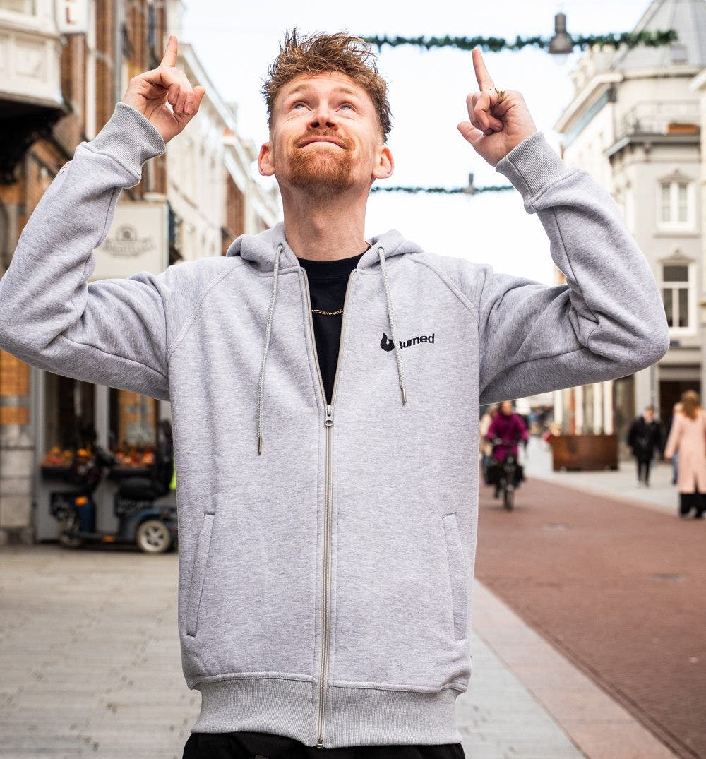Iemand van Burned in een grijze hoodie met het Burned-logo wijst omhoog in de Hinthamerstraat