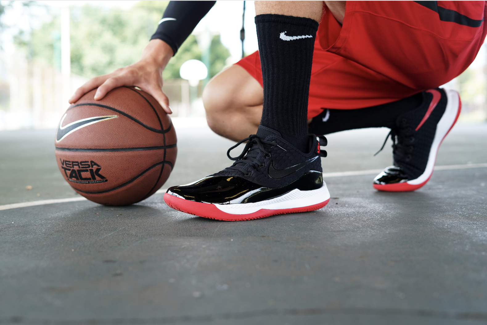 Je ziet een man op z'n hurken vanaf de middel die een. basketbal vasthoudt op de grond.