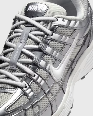 Nike P-6000 sneaker in wit en zilver met retro hardloopdesign, ademend mesh bovenwerk en comfortabele demping. Verkrijgbaar bij Burned Sports Den Bosch, dé specialist in sneakers, basketbal- en sportartikelen.