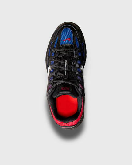 Nike P-6000 sneaker in zwart met blauw-rode fade, geïnspireerd op de hardloopstijl van de jaren 2000. Voorzien van ademend mesh, overlays van synthetisch materiaal en comfortabele demping. Verkrijgbaar bij Burned Sports in Den Bosch, specialist in sneakers, basketbal- en sportartikelen.