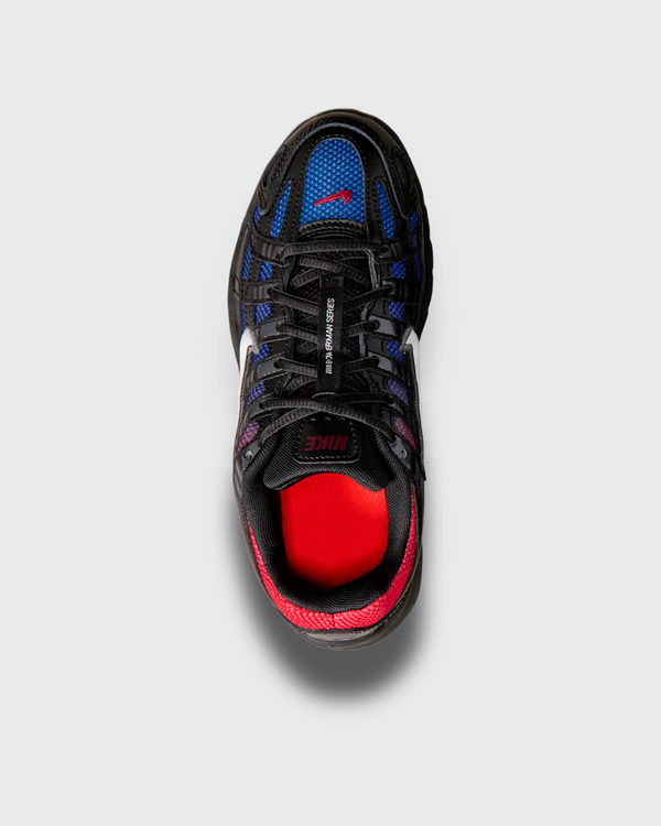Nike P-6000 sneaker in zwart met blauw-rode fade, geïnspireerd op de hardloopstijl van de jaren 2000. Voorzien van ademend mesh, overlays van synthetisch materiaal en comfortabele demping. Verkrijgbaar bij Burned Sports in Den Bosch, specialist in sneakers, basketbal- en sportartikelen.