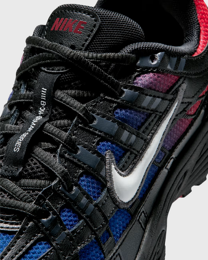 Nike P-6000 sneaker in zwart met blauw-rode fade, geïnspireerd op de hardloopstijl van de jaren 2000. Voorzien van ademend mesh, overlays van synthetisch materiaal en comfortabele demping. Verkrijgbaar bij Burned Sports in Den Bosch, specialist in sneakers, basketbal- en sportartikelen.