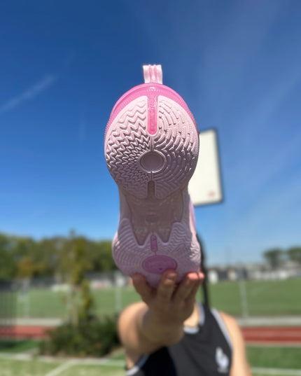 PEAK Flash 6 Basketbalschoen Roze Zoolaanzicht word vastgehouden door man met basketbal veld in achtergrond