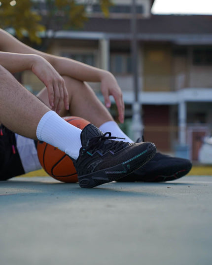anta kai 2 triple black basketbalschoenen on feet sitting with basketbal
