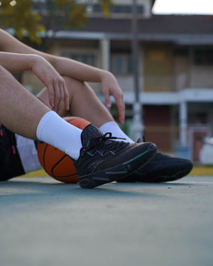 anta kai 2 triple black basketbalschoenen on feet sitting with basketbal