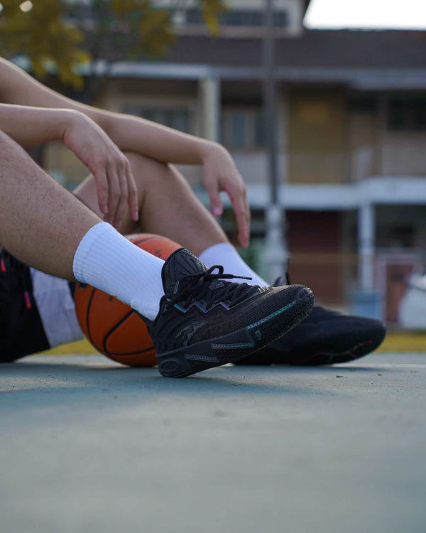 anta kai 2 triple black basketbalschoenen on feet sitting with basketbal
