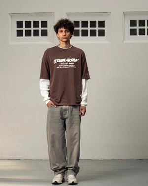 Goodies Sportive Records Longsleeve bruin, gedragen door een model op wijde grijze jeans, vooraanzicht.
