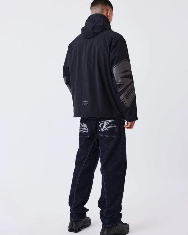 Project X Paris Tag Stiksel Jeans, gedragen onder een windjack, achteraanzicht met tag-logo.