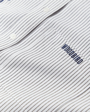 Detail van het blauwe Woodbird-borduursel op het gestreepte overhemd