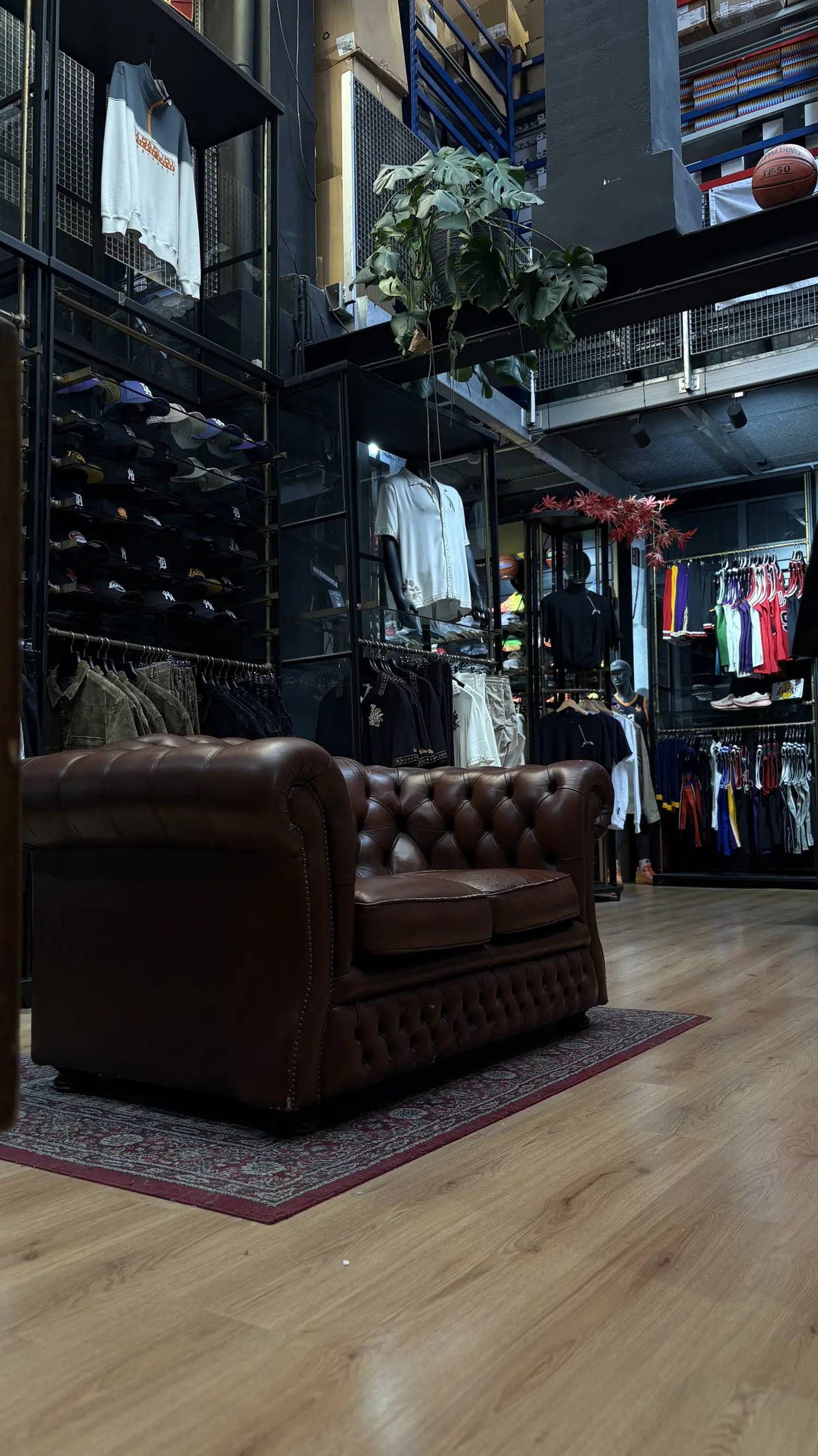 Leren Chesterfield-bank voor een wand met petten, met basketbaljerseys en kleding in de Burned Sports winkel in Den Bosch