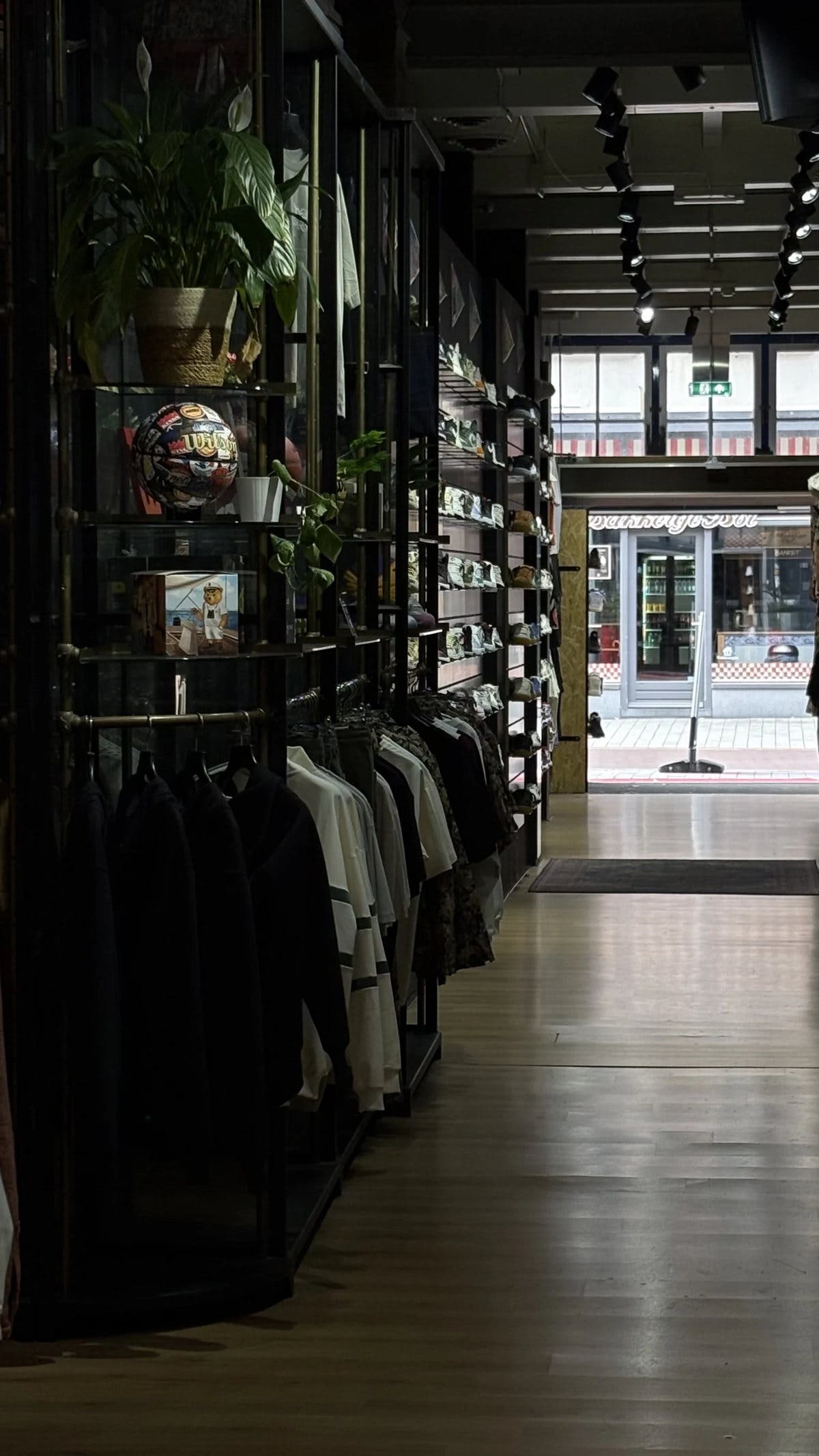 De hoofdgang van Burned Sports in Den Bosch: houten vloer, zwarte rekken met streetwear en sneakers en daglicht uit de etalage