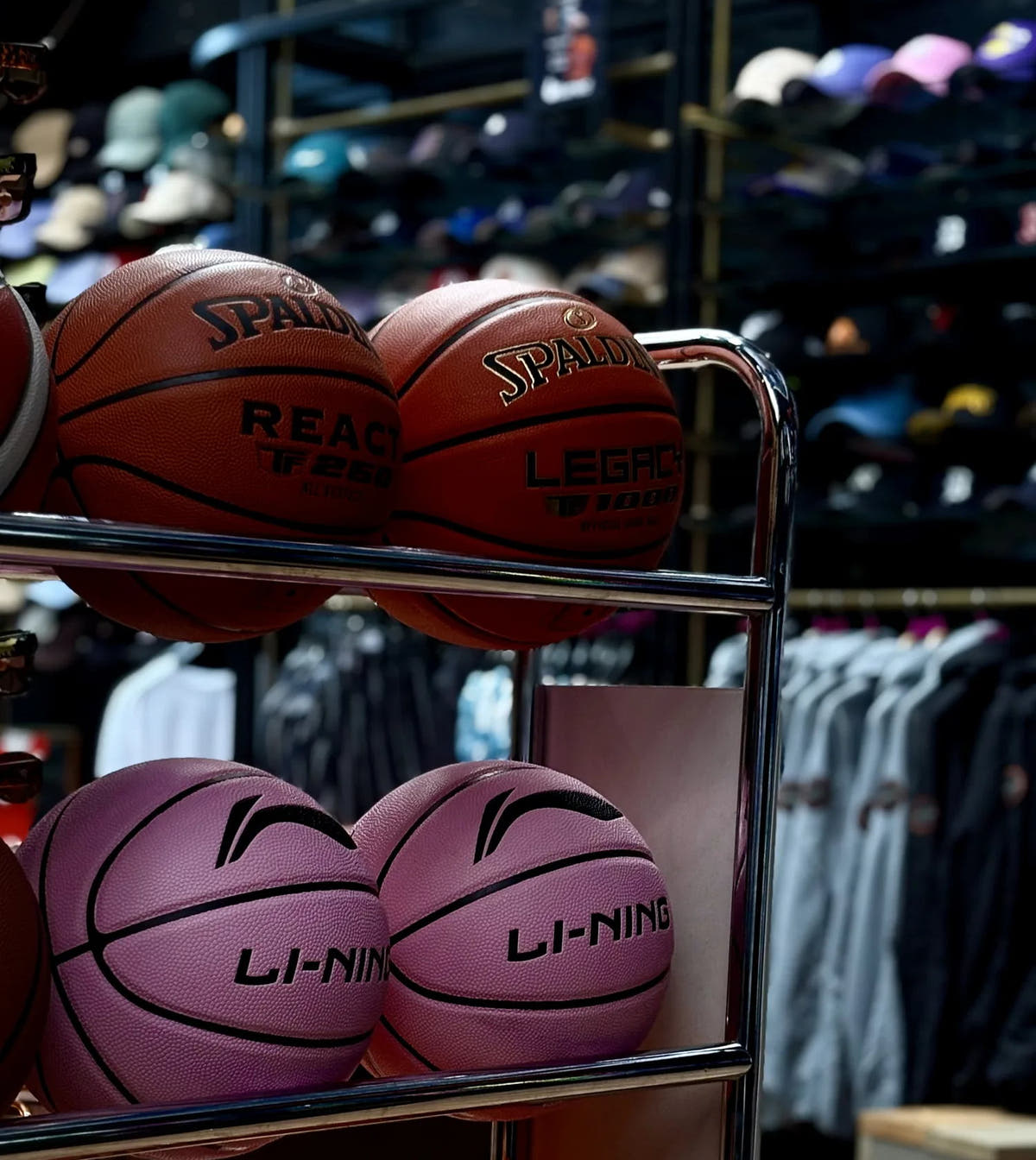Het ballenrek in de winkel van Burned in Den Bosch: Spalding-, Li-Ning- en Wilson-basketballen, met de pettenwand erachter