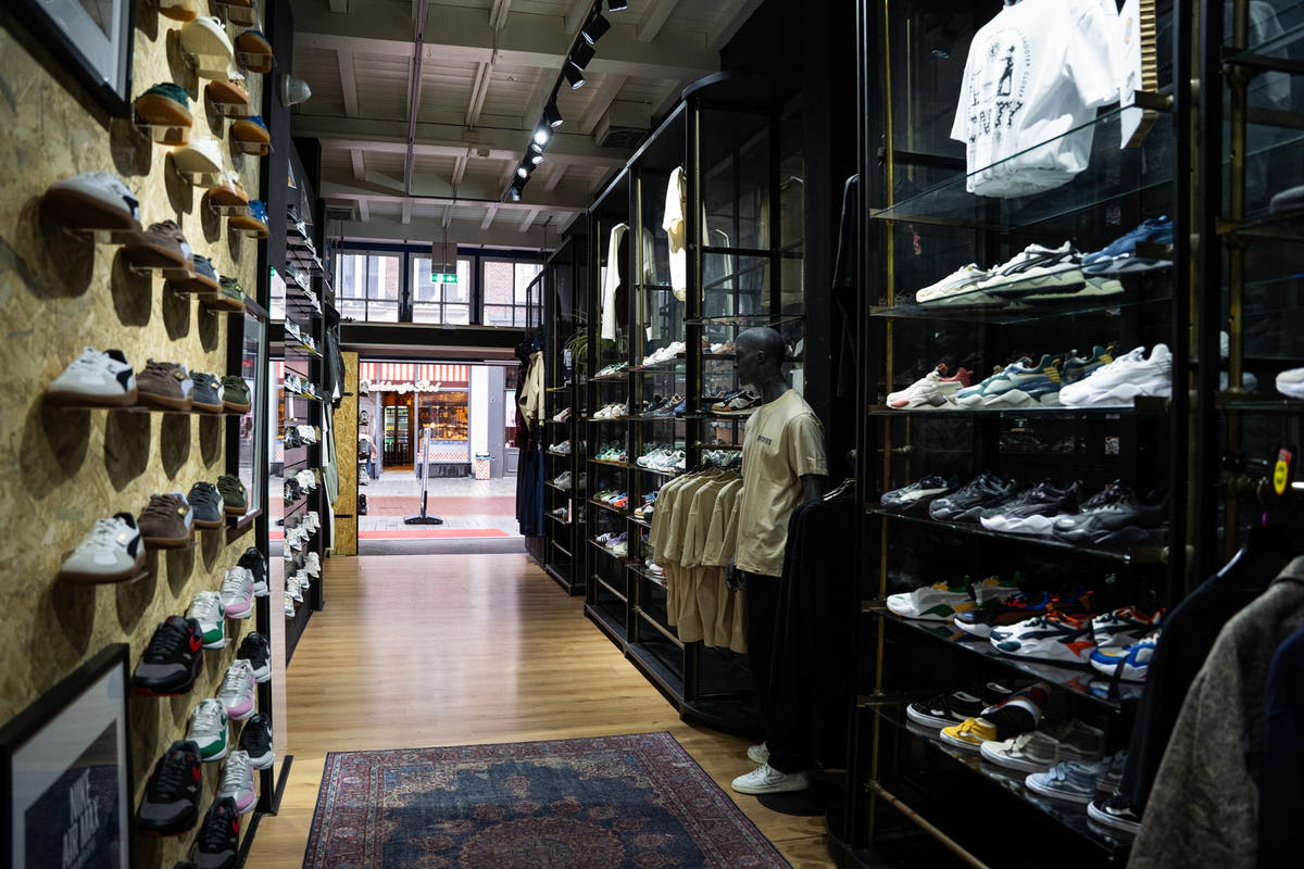 De winkelgang van Burned Sports: links een wand vol sneakers, rechts vitrines met sneakers en kleding, achterin de etalage en de straat