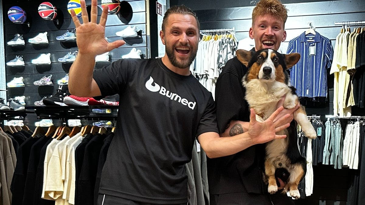 Twee mensen van Burned zwaaien in de winkel; een van hen heeft een hond op de arm
