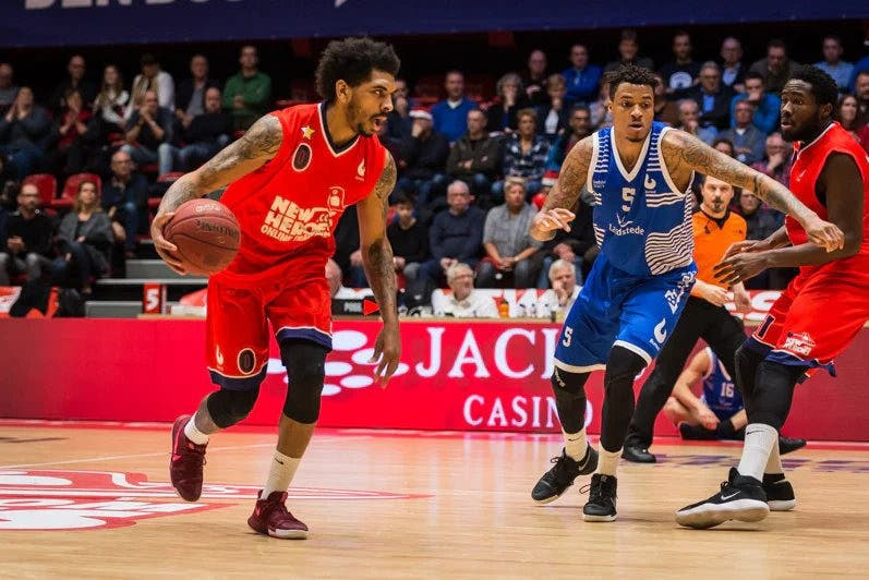 Een basketbalwedstrijd: spelers in rode en blauwe gesublimeerde tenues